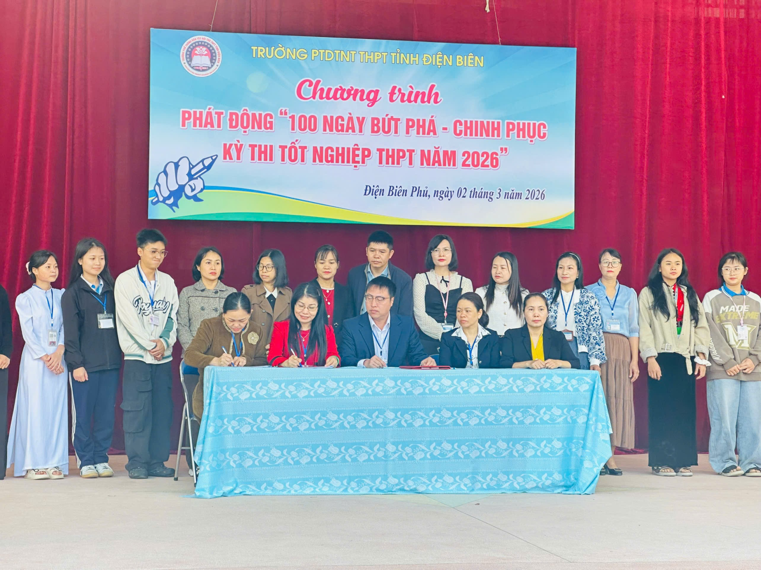 ''A group of people standing in front of a banner

Description automatically generated''